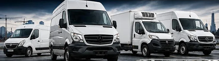A fleet of white commercial vans outside the workshop